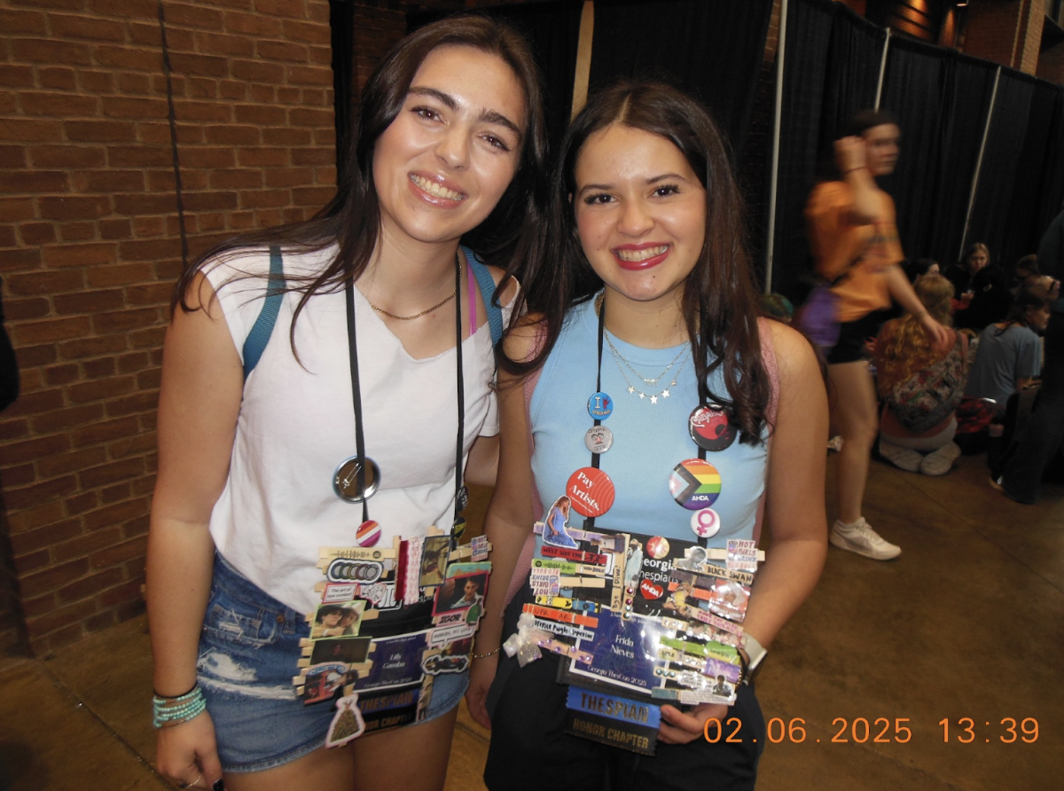 Lilly Gamba (‘25) and Frida Nieves (‘25) are showing off their Thescon badges, which are decorated with pins. 
Photo courtesy of Gamba.
